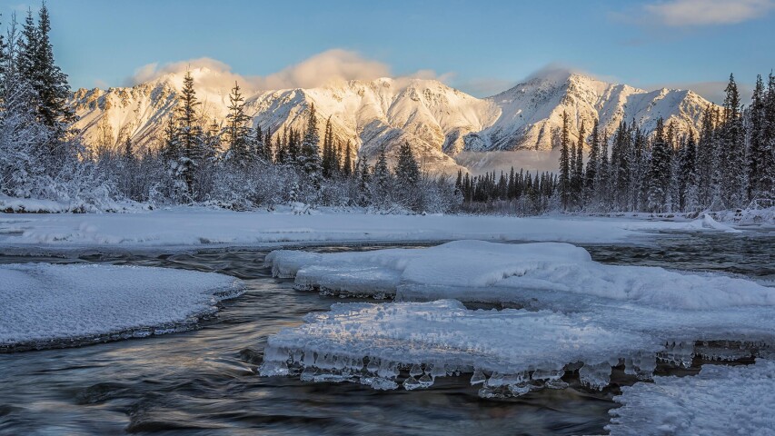 远处有白雪皑皑的山峦在一条溪流后面