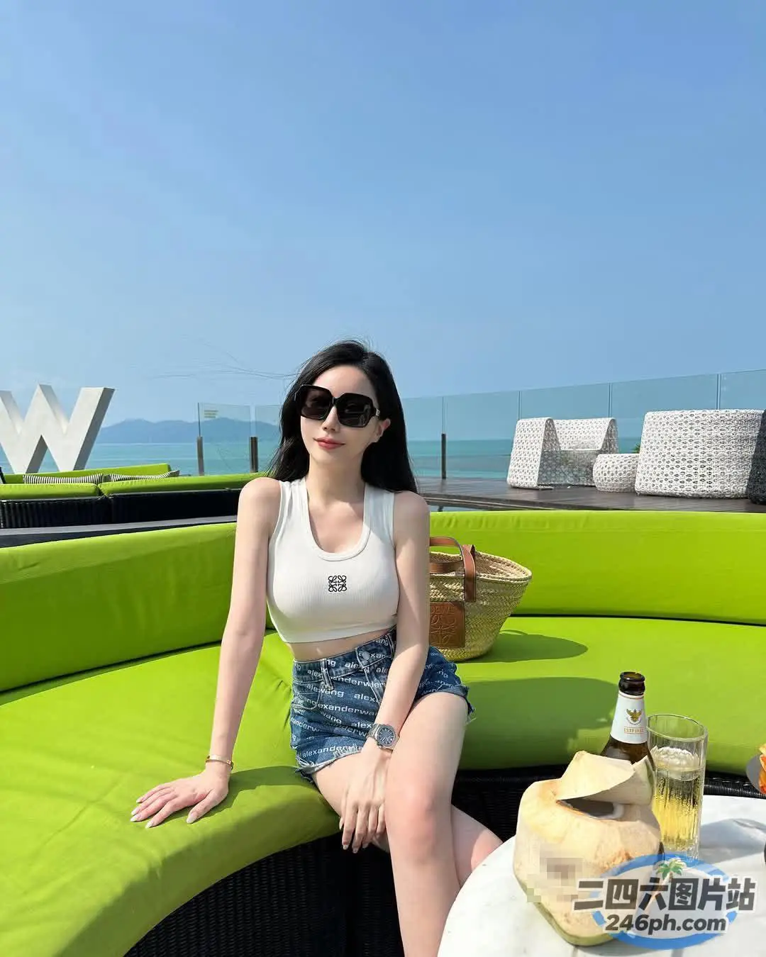 一个女人坐在绿色沙发上，手里拿着一瓶酒