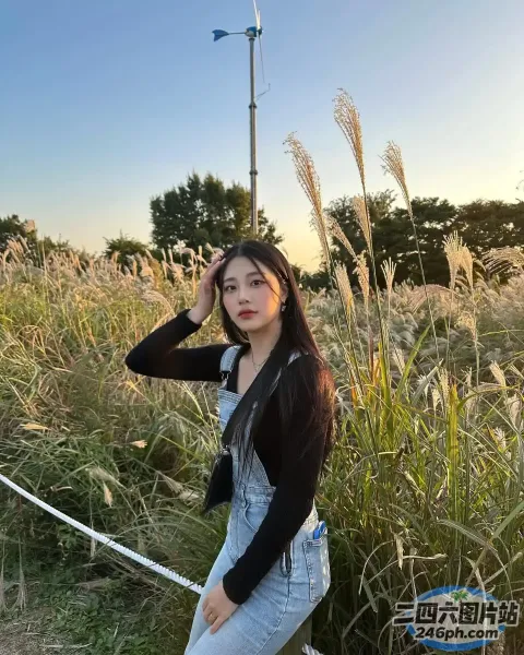 一名身穿工作服和黑色衬衫的女子在田野里摆姿势