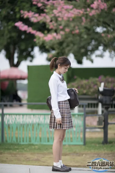 人行道上站着一个女人，手里拿着一个袋子