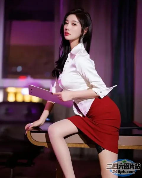 一个穿着红色裙子的女人坐在桌子上，手里拿着一台笔记本电脑
