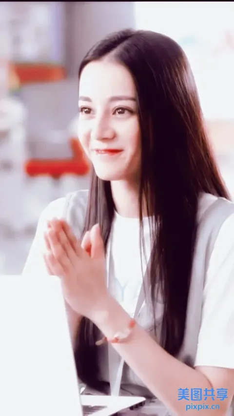 有一个女人坐在一张桌子旁，拿着笔记本电脑