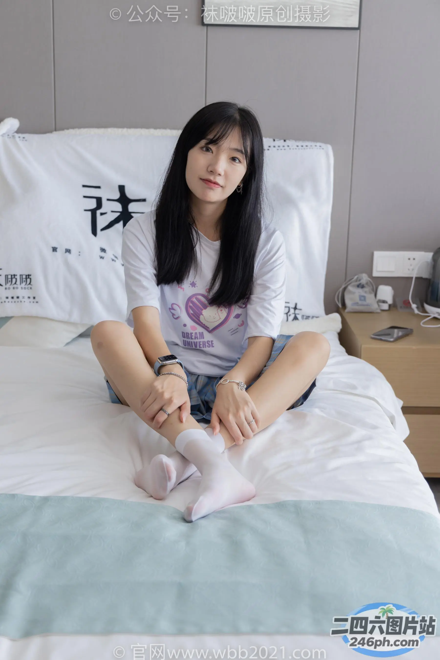 阿拉菲坐在床上，手里拿着一个白色的枕头和一件白色的衬衫