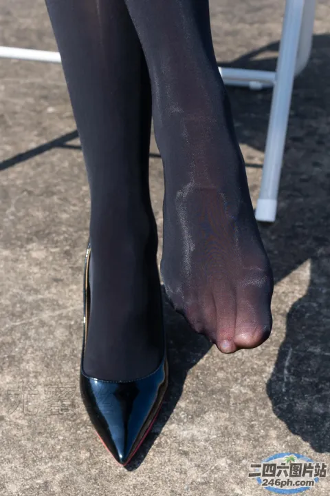 有一个穿着黑色鞋子的女人的腿和一把白色的椅子