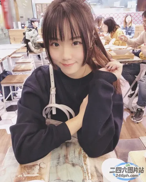 桌旁坐着一个年轻的女孩，手里拿着一个甜甜圈