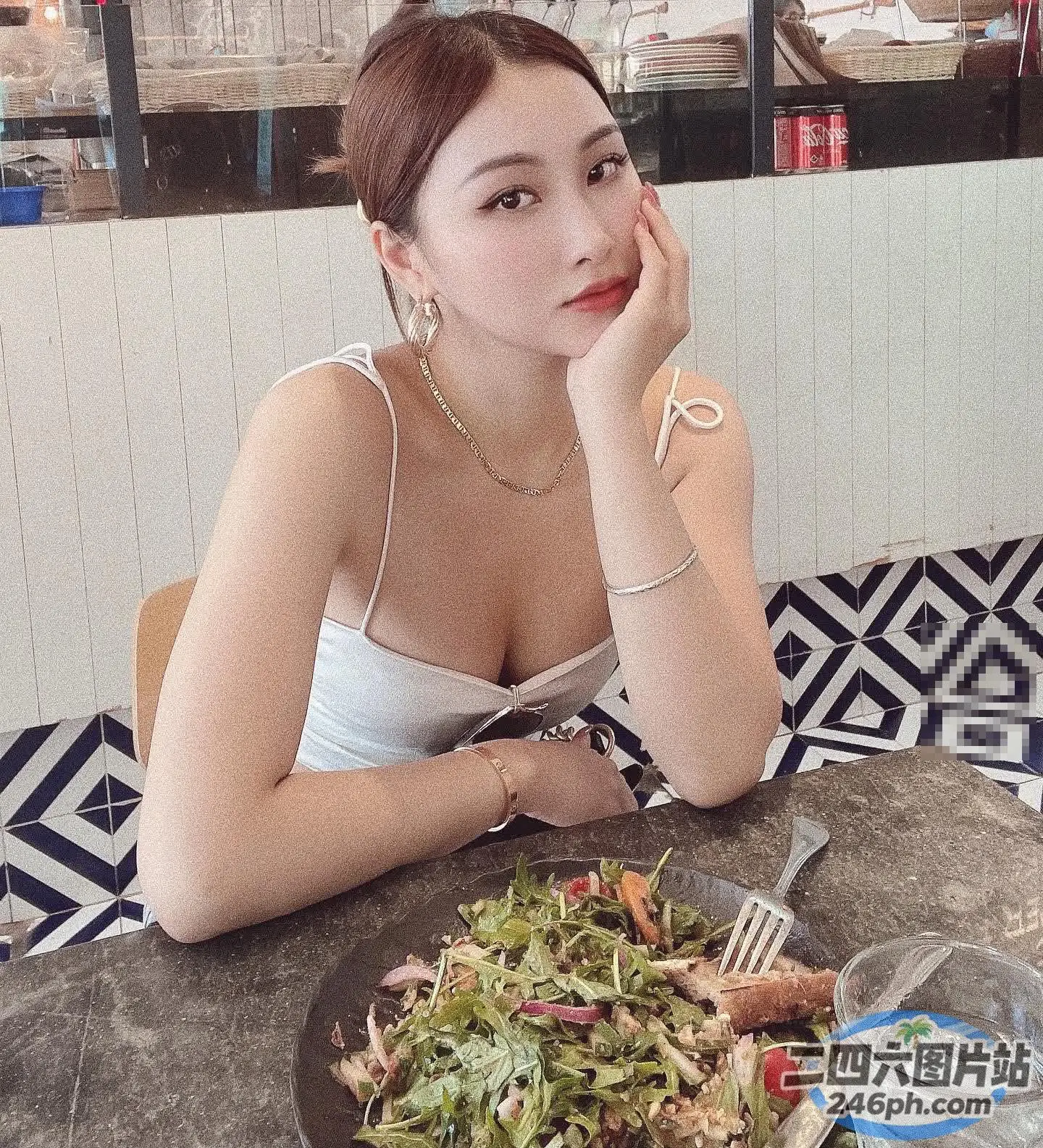 坐在桌子旁的女人，手里拿着一盘食物和一把叉子