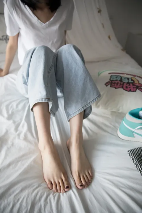 坐在床上，双脚放在枕头上的阿拉菲德女人