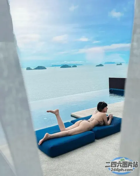 泳池边的蓝色躺椅上躺着一个女人