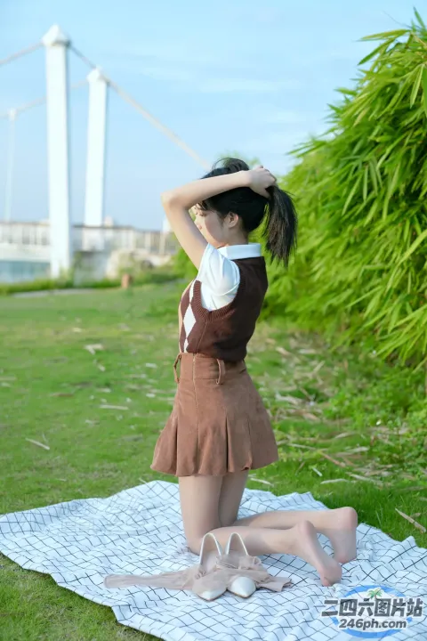 有一个女人坐在草地上的毯子上