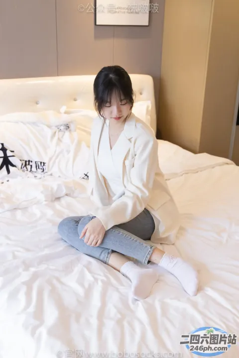 阿拉菲坐在床上，铺着一条白色的毯子和一件白色的夹克