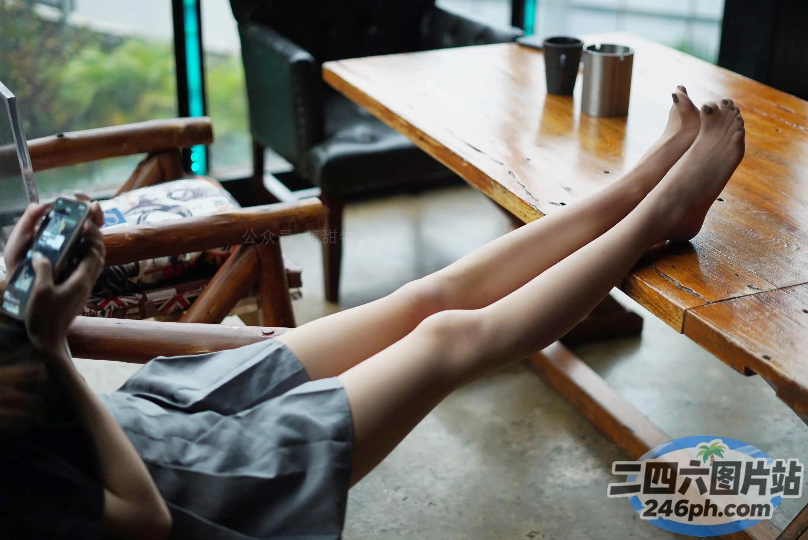 桌旁坐着一个人，手里拿着手机