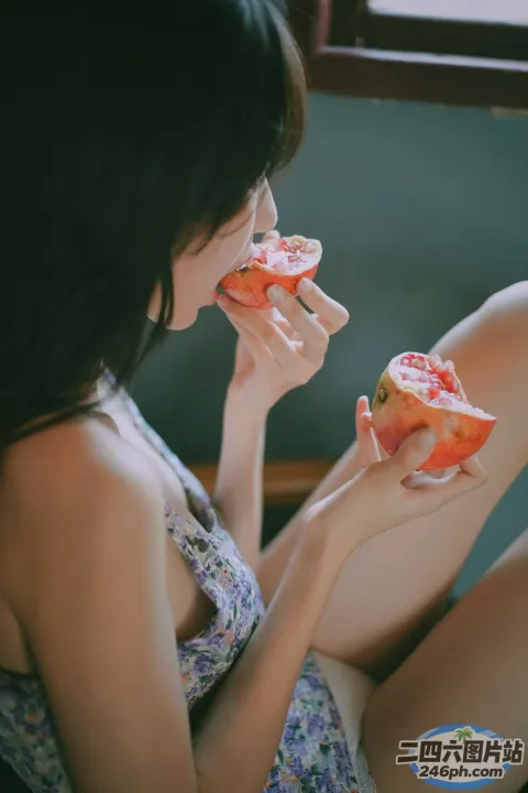 有个女人坐在床上吃着一块水果