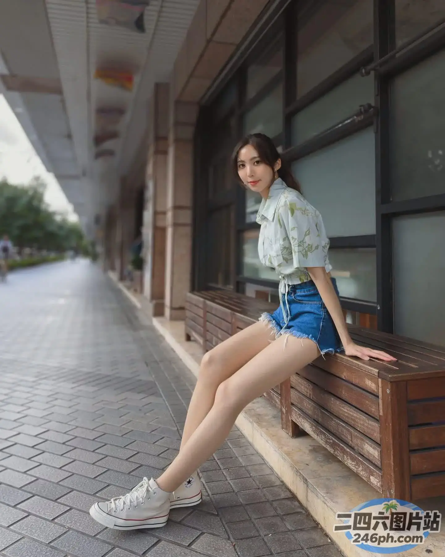 有一位女士坐在一栋楼前的长凳上