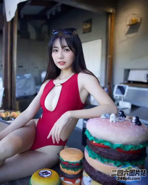 身穿红色泳衣的 araffe 女士坐在一个大汉堡蛋糕旁边
