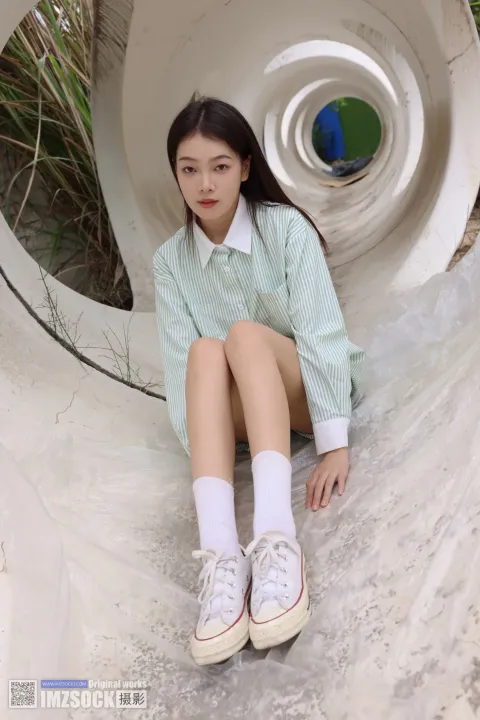 一个女人坐在一根大管子上，双腿交叉