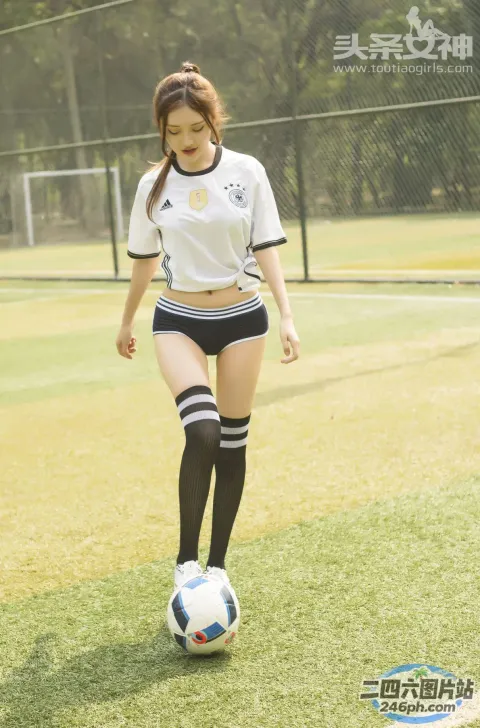 身穿白衬衫和黑色短裤的 araffe 女孩踢足球