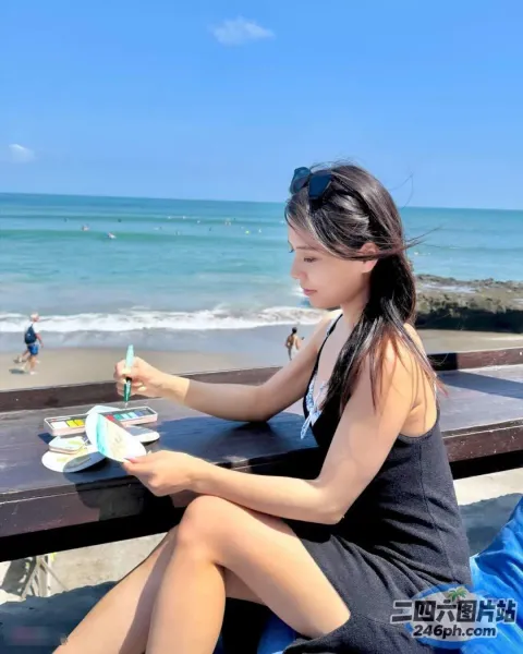 女人坐在桌子旁，手里拿着一本书和一杯饮料