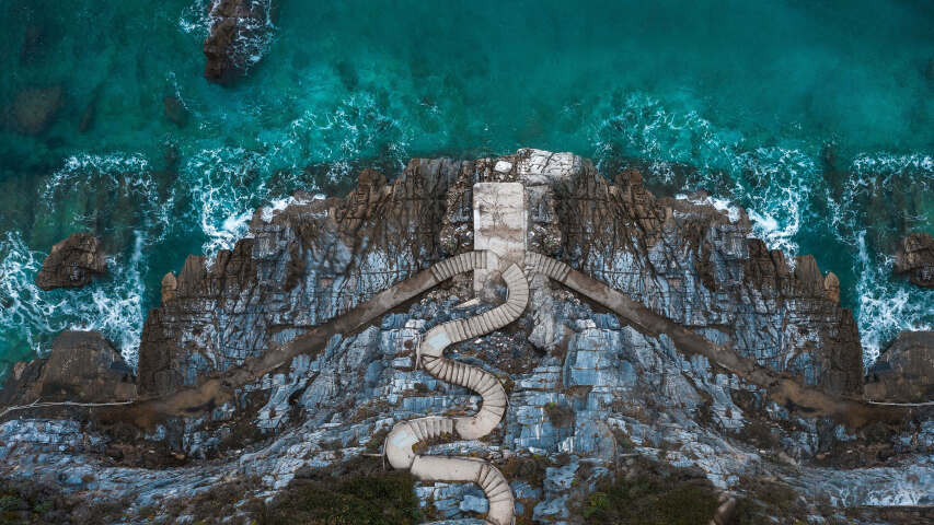 通往有水体的海滩的石头人行道的鸟瞰图
