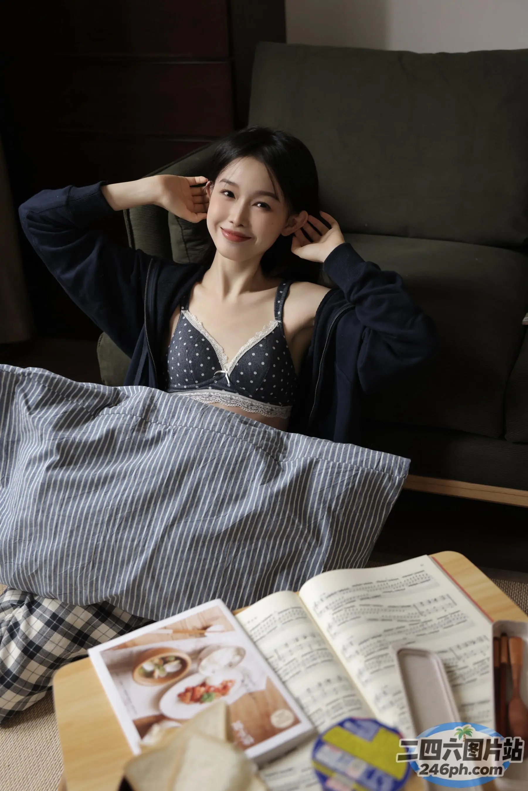 女人坐在沙发上，手里拿着一本书和一个枕头