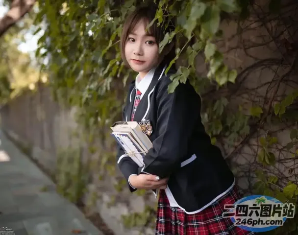有一个穿着校服的小女孩，手里拿着一本书