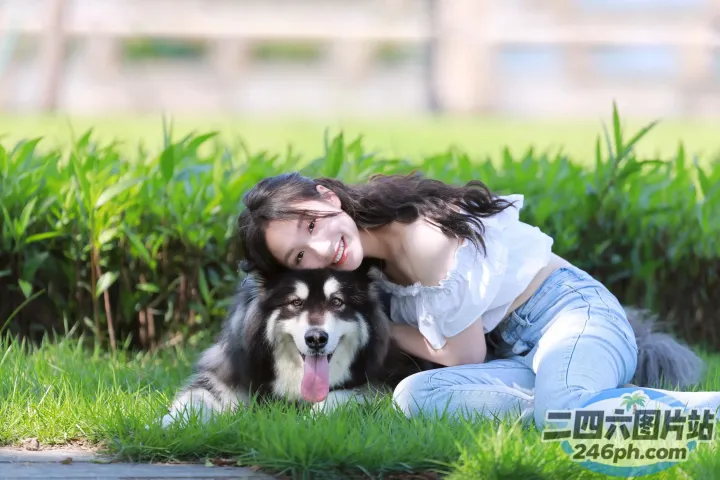 草地上坐着一个女人和一只狗