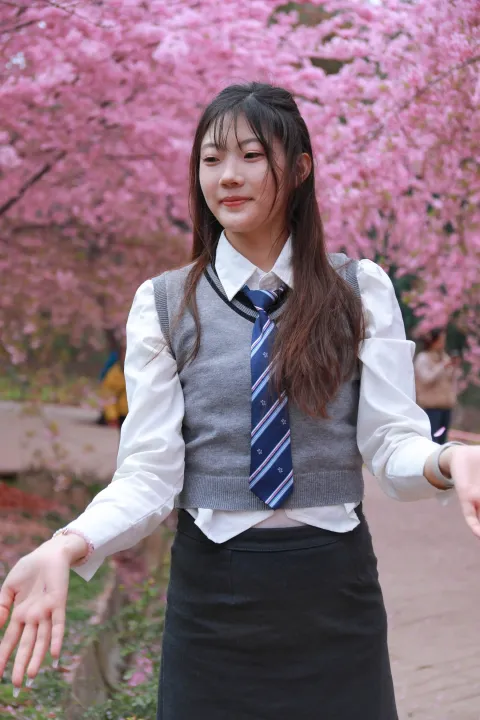 树前站着一个穿着裙子、打着领带的女人