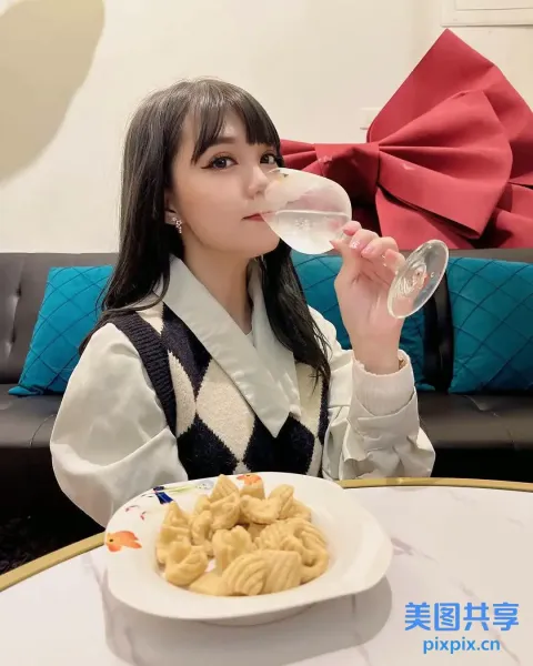 Araffe 女孩坐在桌子旁用玻璃杯喝水
