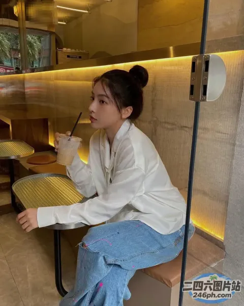 有个女人坐在长凳上，手里拿着一杯饮料