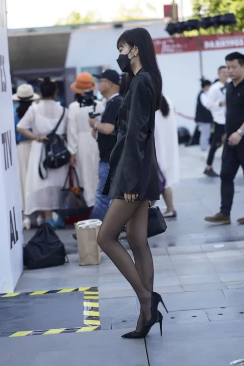 身穿黑色夹克和黑色高跟鞋的阿拉菲女子走在街上