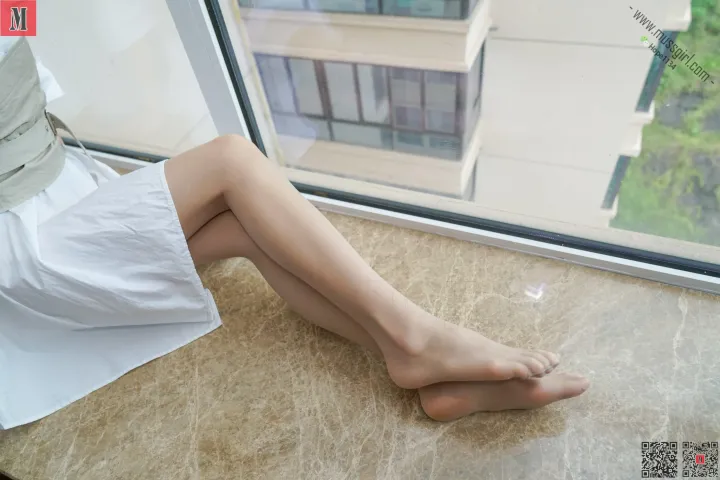 Araffe 坐在窗前的地板上，可以看到城市的景色