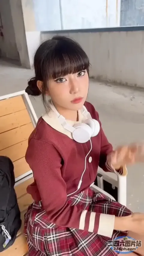 有一个年轻女孩坐在长凳上，戴着耳机