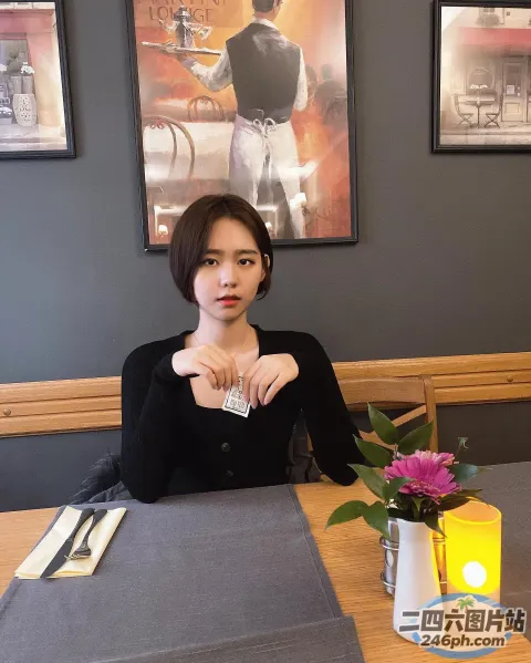 有个女人坐在桌子旁，手里拿着一杯酒