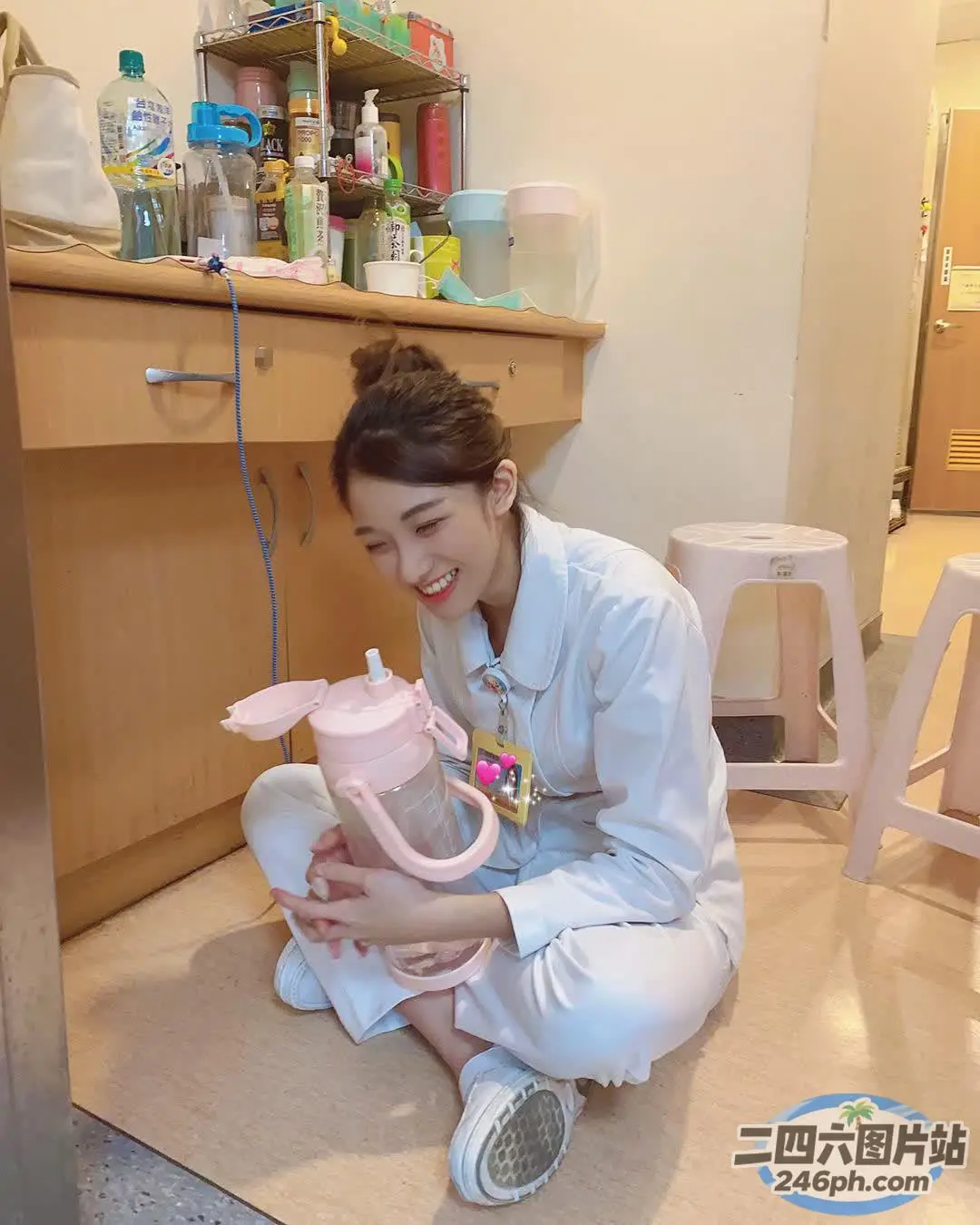 身穿白衬衫的 Arafed 女子在厨房里拿着一台粉红色的搅拌机