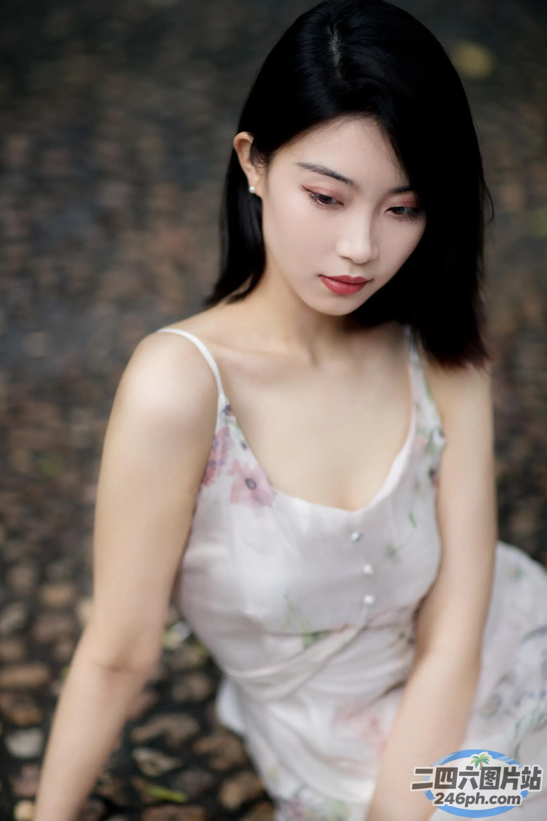 一个穿着白色连衣裙的女人坐在岩石上的特写