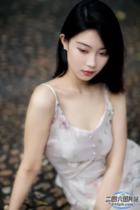一个穿着白色连衣裙的女人坐在岩石上的特写