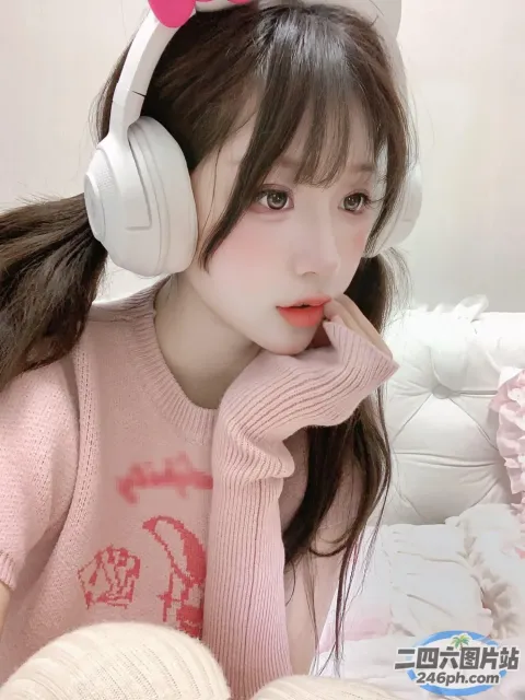 戴着耳机的 Araffe 女孩坐在床上，穿着粉红色毛衣