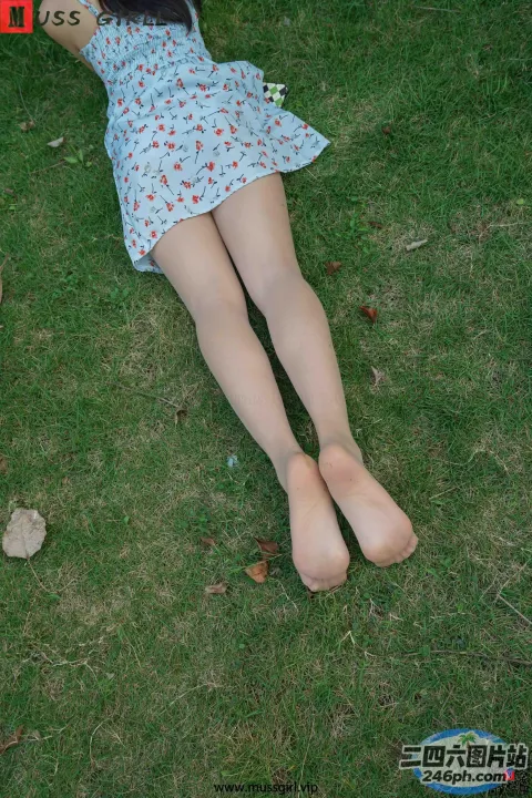 有一个女人双腿交叉躺在草地上