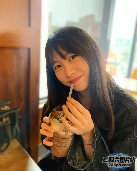 坐在桌子旁的女人，手里拿着饮料和吸管