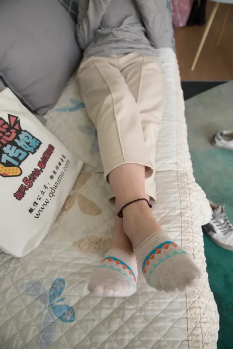 有人躺在床上，手里拿着一本书和一双袜子