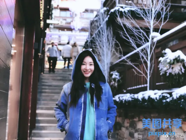 身穿蓝色夹克和蓝色连帽衫的阿拉夫女人站在石墙前