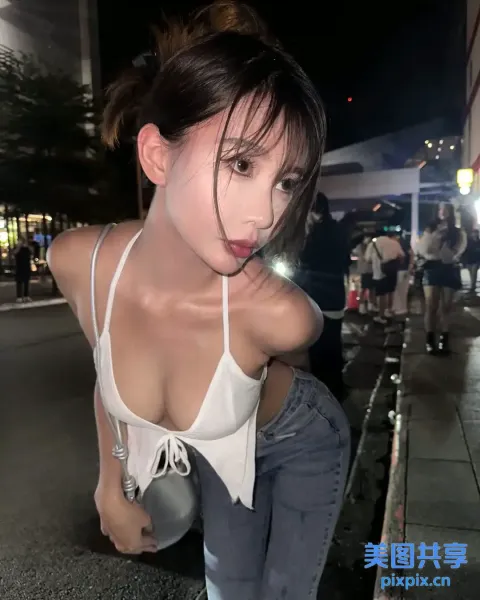 街头穿着白色上衣和牛仔裤的 Araffed 亚洲女人