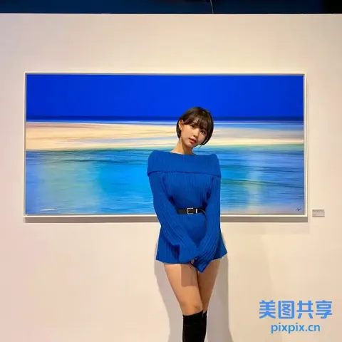 阿拉菲在一幅海滩风景画前摆姿势