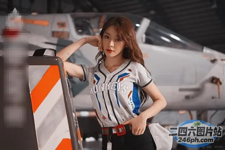 身穿棒球服的女子倚靠在飞机前的栏杆上