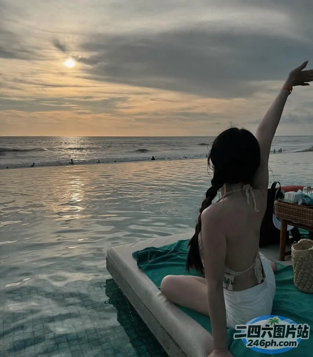 女人坐在水中的木筏上，张开双臂