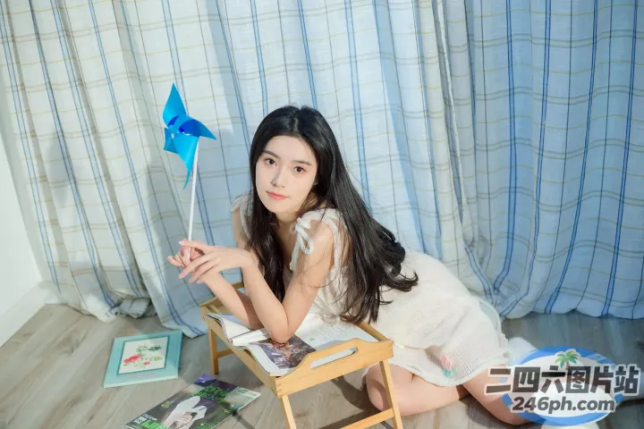 地板上坐着一个女人，手里拿着一个蓝色的风车