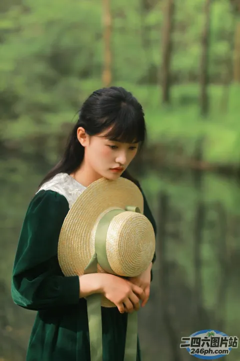 有个身穿绿色连衣裙的女人，手里拿着一顶帽子
