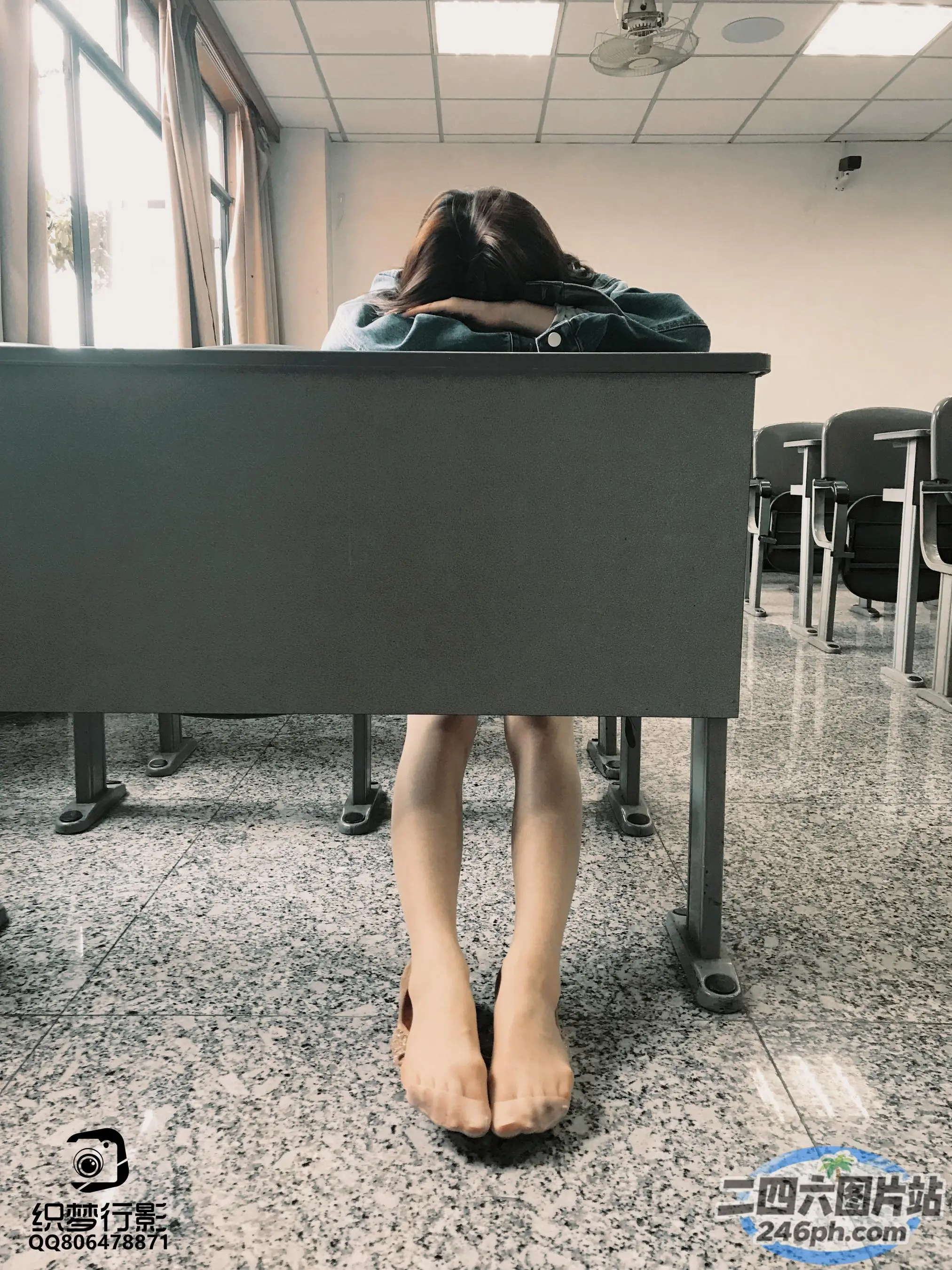 有一个女人坐在桌子前，双腿放在桌子上
