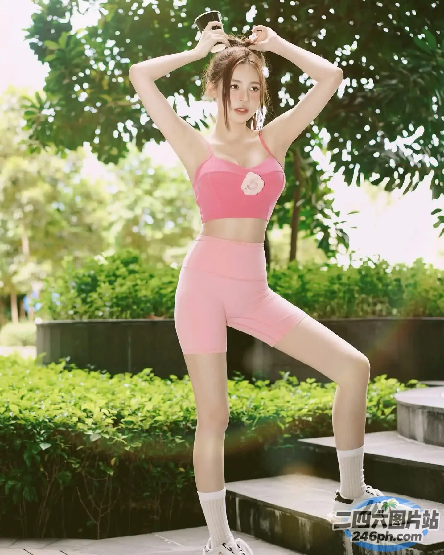 一名身穿粉红色运动服的女子在公园的台阶上摆姿势