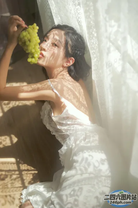 有一个穿着白色连衣裙的女人，手里拿着一串葡萄
