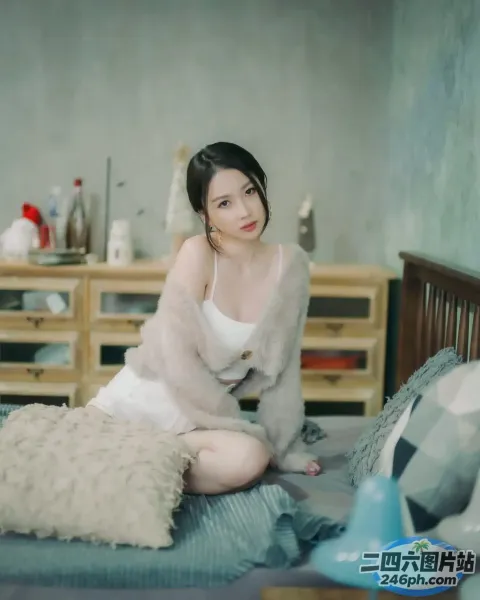 有一个女人坐在床上，上面盖着一条毯子
